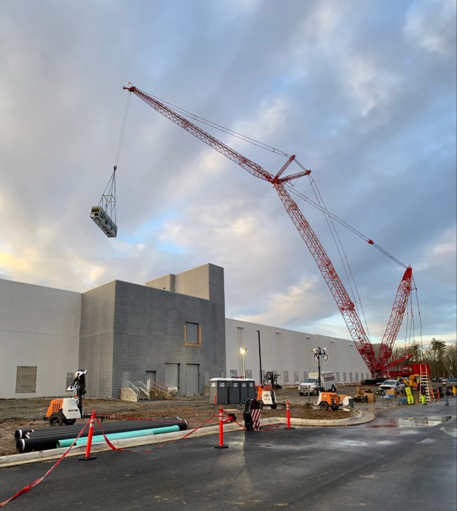 Crane lifting a chiller onto the roof of a building